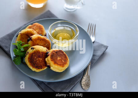 Cottage cheese pancakes with blueberry, honey, jam and coffee. Ukrainian syrniki, cottage cheese fritters or pancakes on gray wooden background. Healt Stock Photo