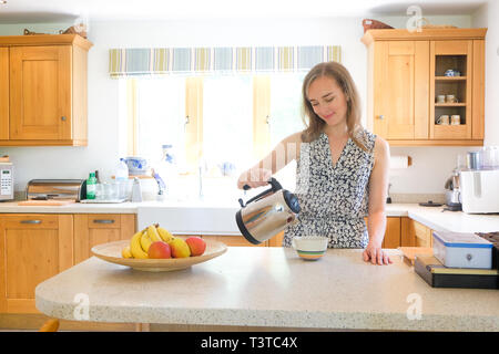 Caucasian woman pouring coffee from pot in kitchen Stock Photo