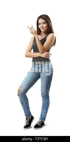 Young woman in jeans and gray top standing in half-turn with right arm across belly and left arm bent in elbow and raised isolated on white background Stock Photo