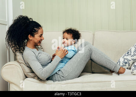 Side view of mother lying on couch and playing with her son Stock Photo