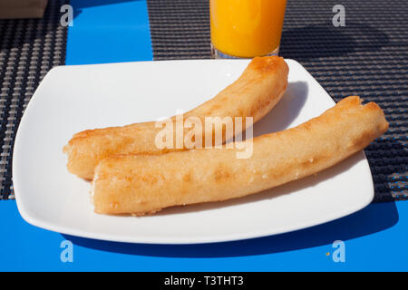 Breakfast with churros and orange juice on a bar table in Andalusia. Stock Photo