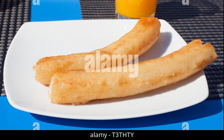 Breakfast with churros and orange juice on a bar table in Andalusia. Stock Photo