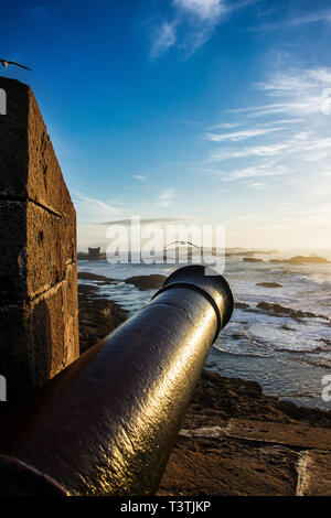Scenic landscape of Atlantic ocean at sunset with old metal cannon in the foreground. Essaouira, Morocco Stock Photo