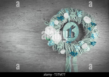 A wreath with Easter motives in front of old wooden background. The colors are washed out to create a vintage look. Cut out rabbit shape. Stock Photo