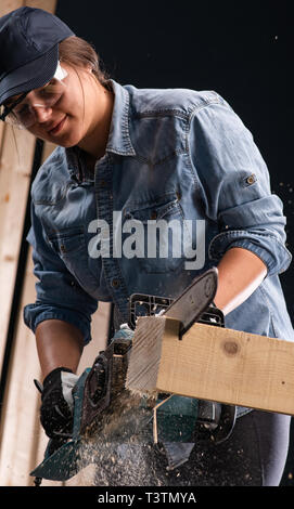 Young woman  using modern electric  saw for ctting wood  in the workshop Stock Photo