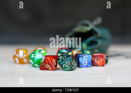 Different colorful role playing dice on table with blurry storage leather bag in backgorund Stock Photo