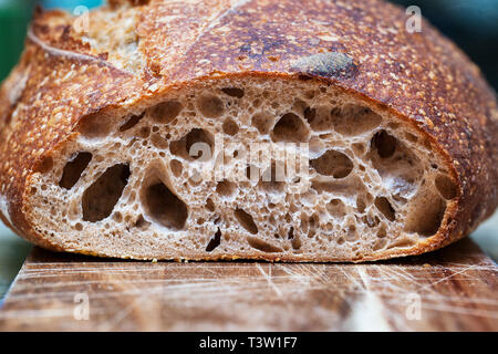 Crusty loaf of freshly baked sourdough bread Focaccia. Slices of sourdough bread on wooden board. Healthy food. Artisan bread crumb texture close-up Stock Photo