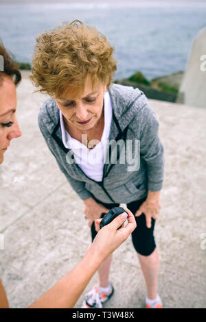 Senior woman looking smart watch with her coach Stock Photo