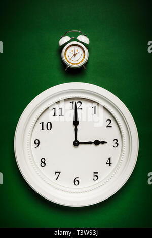 two different clocks placed on a green background Stock Photo