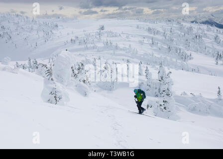 Caucasian snowshoer walking up snowy hillside Stock Photo