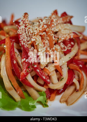 Red pepper salad with squid is beautifully decorated with fresh herbs and served to the table. Stock Photo