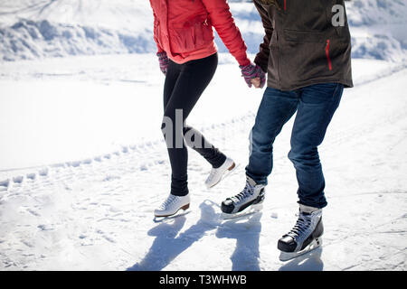 Caucasian couple ice skating on snowy frozen lake Stock Photo