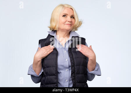 blonde old woman holding hands on chest feeling touched or pleased Stock Photo