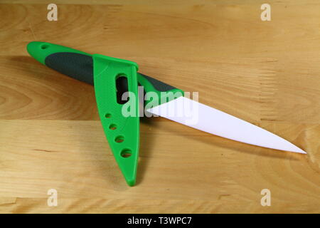 Ceramic knife with green and black handle and white blade and its green protection Stock Photo