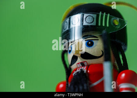 Side view of a nutcracker soldier on against a green background. Nutcracker soldier figurine in helmet. Stock Photo