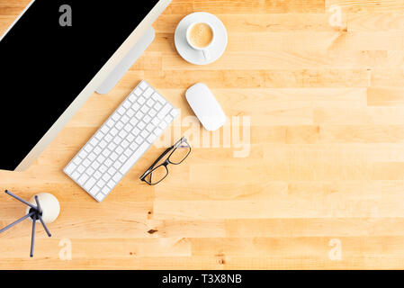 Desktop computer. Top view of wooden office desk with large desktop computer, keyboard, mouse, scented sticks, glasses, plant and cup of coffee. All i Stock Photo