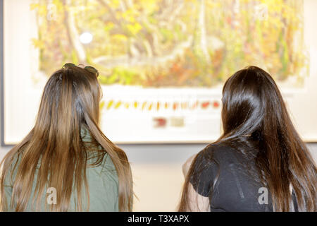 Two young women looking at a painting in a an art gallery Stock Photo