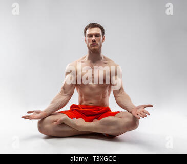 A man with his eyes closed and muscular body sitting in the lotus position Stock Photo