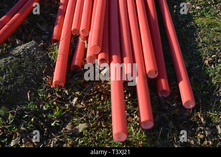 Stack red plastic electricity cable protection pipes on street Stock Photo