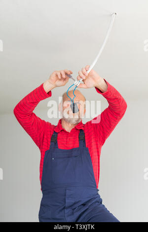 Close up picture of a senior electrician working in a new apartment - electric installation concept Stock Photo
