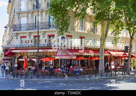 PARIS, FRANCE - JULY 21, 2017: Typical cafe brasserie with sidewalk tables with people and tourists sitting in a sunny summer day in Paris, France Stock Photo