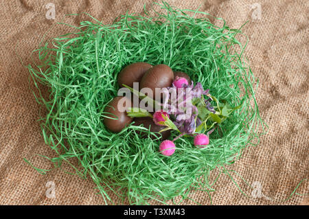 Easter Decoration with Chocolate Eggs and Wildflowers in a Decorative Grass Nest Stock Photo