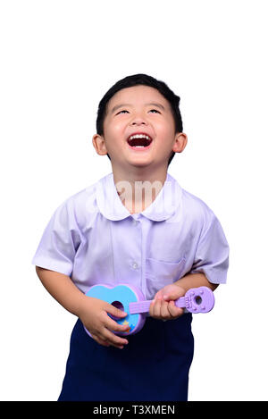 Asian Thai kindergarten student kid in school uniform playing toy guitar isolated on white background with clipping path. musical concept idea. Stock Photo