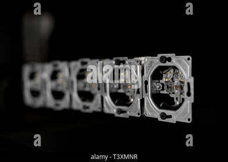 Five outlets in line, disassembled and mounted in black glass wall. Stock Photo