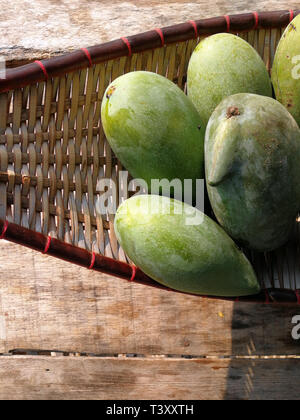 green mango on basket and old wooden desk ,group of mangoes fruit, sour and high vitamin for healthy. Stock Photo