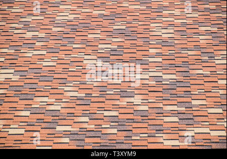 Roof from multi-colored bituminous shingles. Patterned bitumen shingles Stock Photo