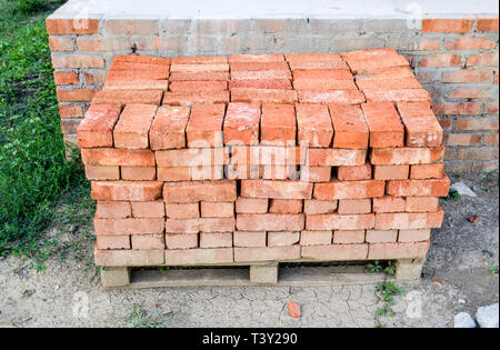 The red brick folded neatly on the foundation of the house. Home construction. Stock Photo