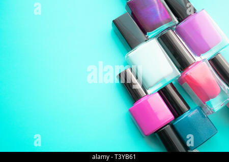 Bottles of nail polish. A group of bright nail polishes on a green background. With empty space on the left. View from above Stock Photo
