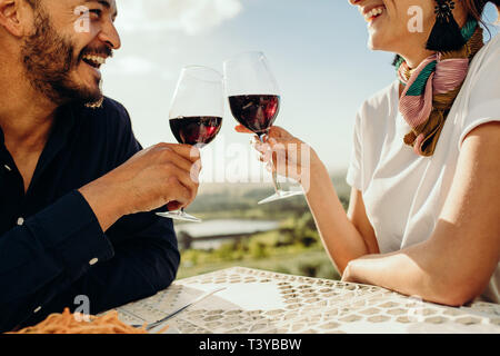 Cropped shot of a happy couple sitting at a restaurant together with a glass of red wine. Close up of a couple on a date talking and spending time wit Stock Photo