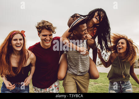 Multiracial group of friends hanging out and having fun outdoors. Young men and women enjoying outdoors on summer day. Stock Photo