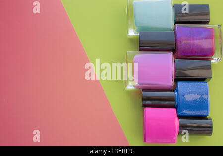 Bottles of nail polish. A group of bright manicures on a pink, green background. With empty space on the left. View from above Stock Photo