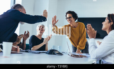 Business people giving each other high five and clapping. Business team celebrating success. Stock Photo