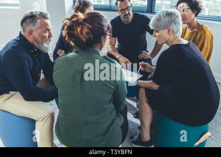 Multi-ethnic group of people sitting together having a meeting. business people having a group discussion on new working strategy. Stock Photo