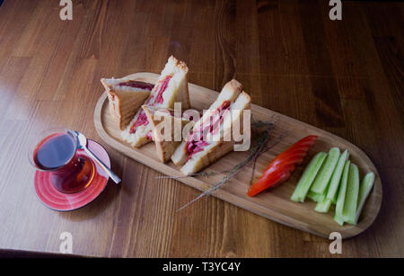 sliced cheddar and sausage toast cucumber tomato tea prepared for breakfast Stock Photo