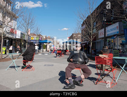 A middle aged man sits in a public space on 37th Road in Jackson Heights, Queens, New York City. Stock Photo