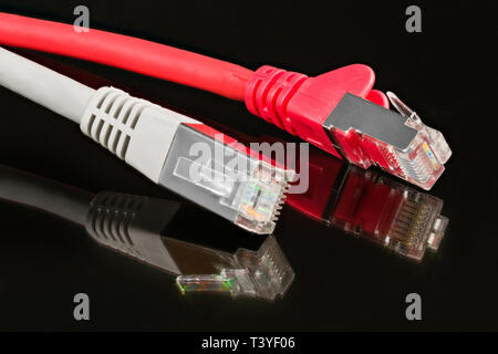 Patch cables. Ethernet network connectors. Artistic detail. Reflection on black shiny background. Red and gray net cords. Still life. STP, FTP wires. Stock Photo