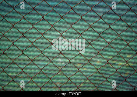 Rusty lattice fence. Old grid. Green striped fabric texture. Double opaque protection. Old metal wire mesh. Rough textile on background. Brown netting Stock Photo