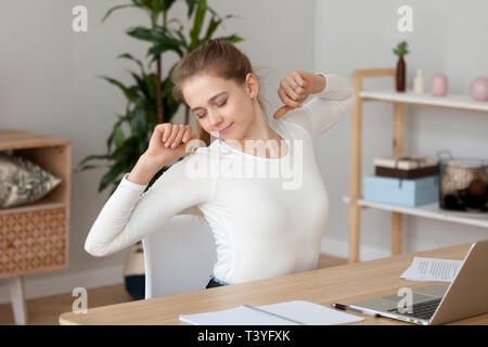 Satisfied young woman stretching, doing exercise at workplace Stock Photo