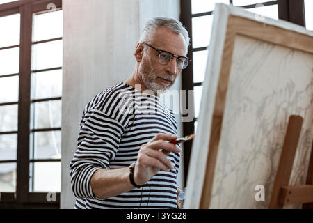 Brush in hands. Dark-eyed famous artist wearing bracelet having painting brush in his hands Stock Photo