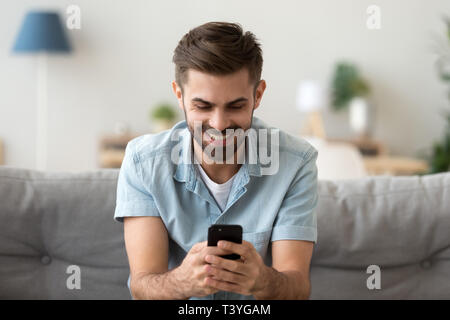 Excited smiling man looking at phone screen, using mobile app Stock Photo