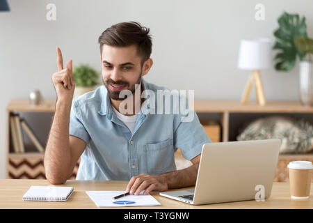 Satisfied man with raised hand thinking about good creative idea Stock Photo
