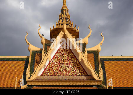 Birds land on and fly around the ornamented roof of the Phochani Pavilion (dance hall) inside the Royal Palace grounds in Phnom Penh, Cambodia. Stock Photo