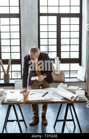 Designer with pencil. Dark-eyed mature interior designer holding pencil while making sketches Stock Photo