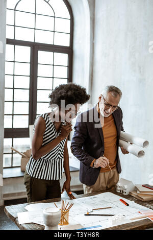 Helping employee. Boss of interior design company helping his employee with some challenging task Stock Photo