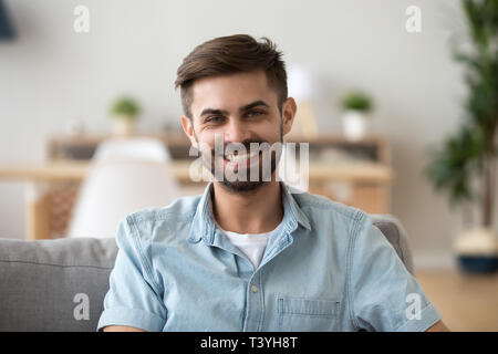 Head shot portrait of happy smiling man sitting on sofa at home Stock Photo