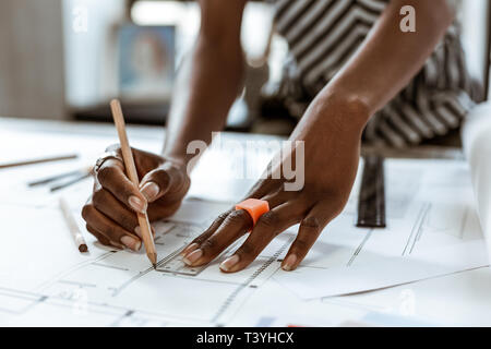 Orange ring. Close up of African-American interior designer wearing orange ring painting sketches Stock Photo